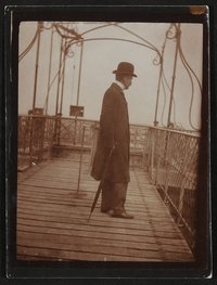 Harry Graf Kessler, mit Schirm und Melone auf einer Holzbrücke stehend