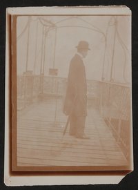 Harry Graf Kessler, mit Schirm und Melone auf einer Holzbrücke stehend